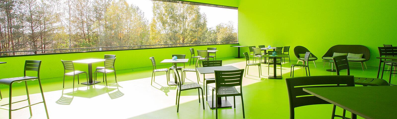 Große überdachte Terrasse mit Tischen und Stühlen darauf.