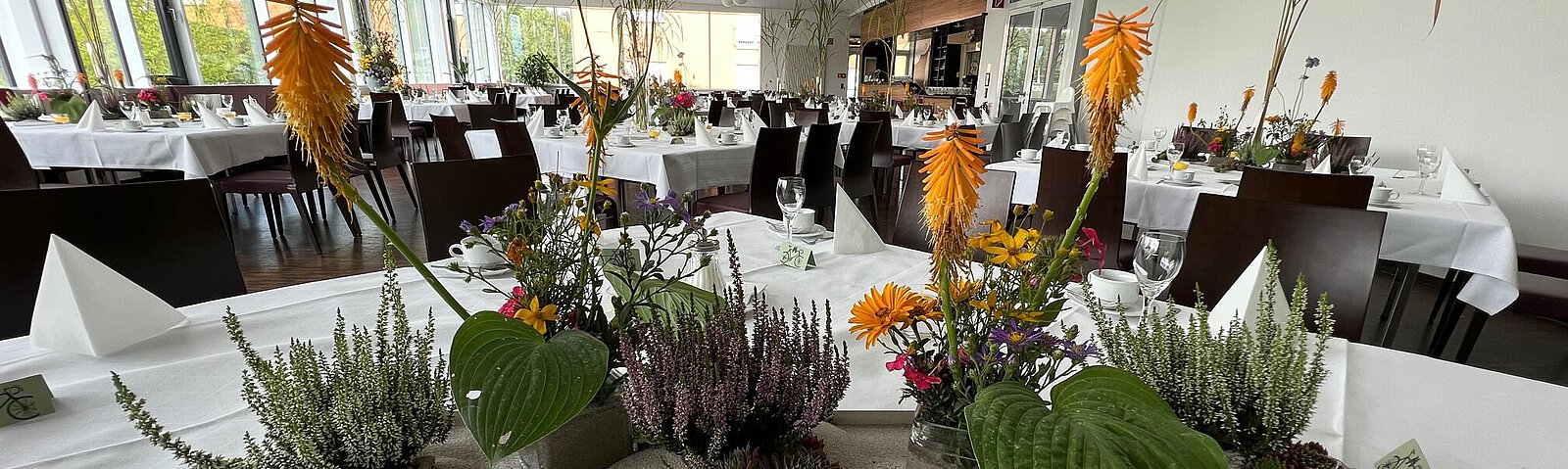 Detailaufnahme von Blumenschmuck auf einem Tisch, ein längliches Tablett mit großblättrigen Orchideen.